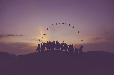 Graduates throwing hats at dusk